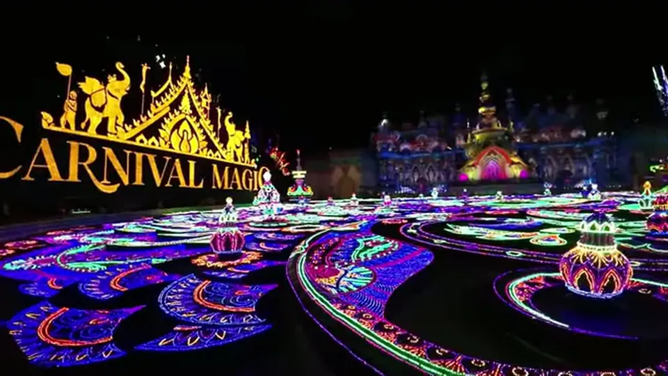 Carnival Magic sign rises above colorful illuminated patterns at night.