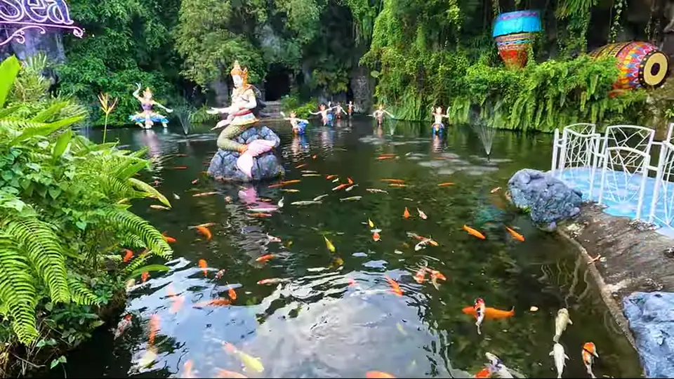 Koi pond with statues, small fountains, and tropical greenery.