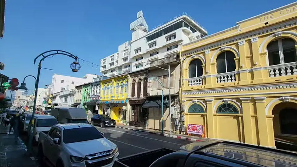 Yellow and pastel shophouses stand beneath a clear blue sky.