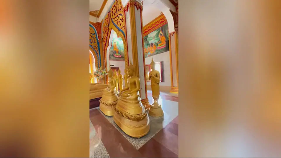 Golden Buddha statues lined beneath richly painted temple arches.