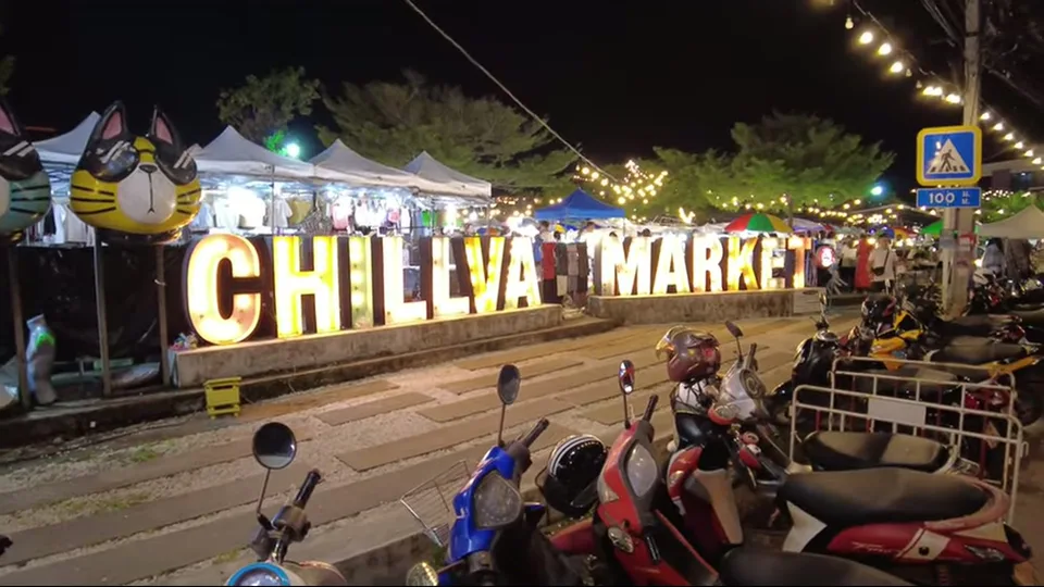 Illuminated CHILLVA sign in front of market stalls at dusk